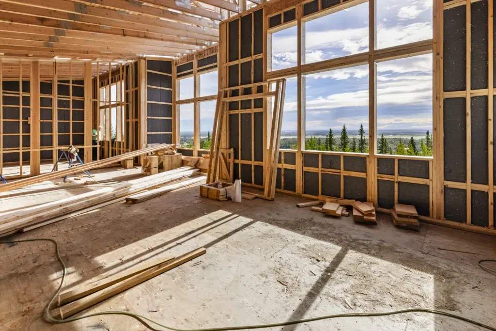 House in construction with sunlight coming through window openings
